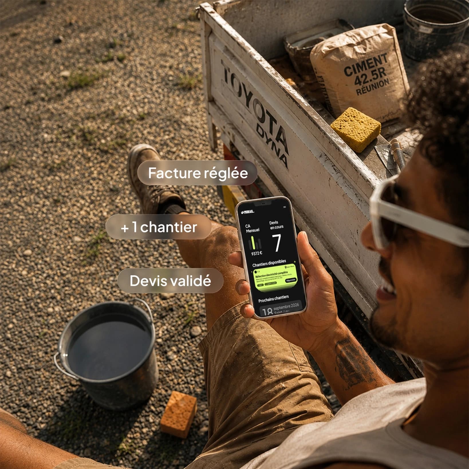 Un artisan consulte ses chantiers Murail sur son téléphone, à l'arrière de son camion.